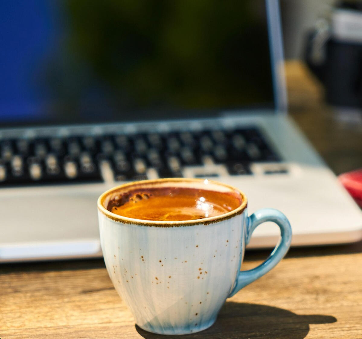 Online therapy in Ontario with Kelly (MSW, RSW). A sunny wooden desk with a laptop, therapy journal, and hot coffee.
